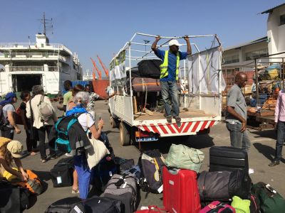 Le piano dans le camion, les valises sous le piano, le camion dans le bateau