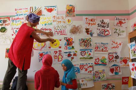 Christine accroche les dessins des enfants